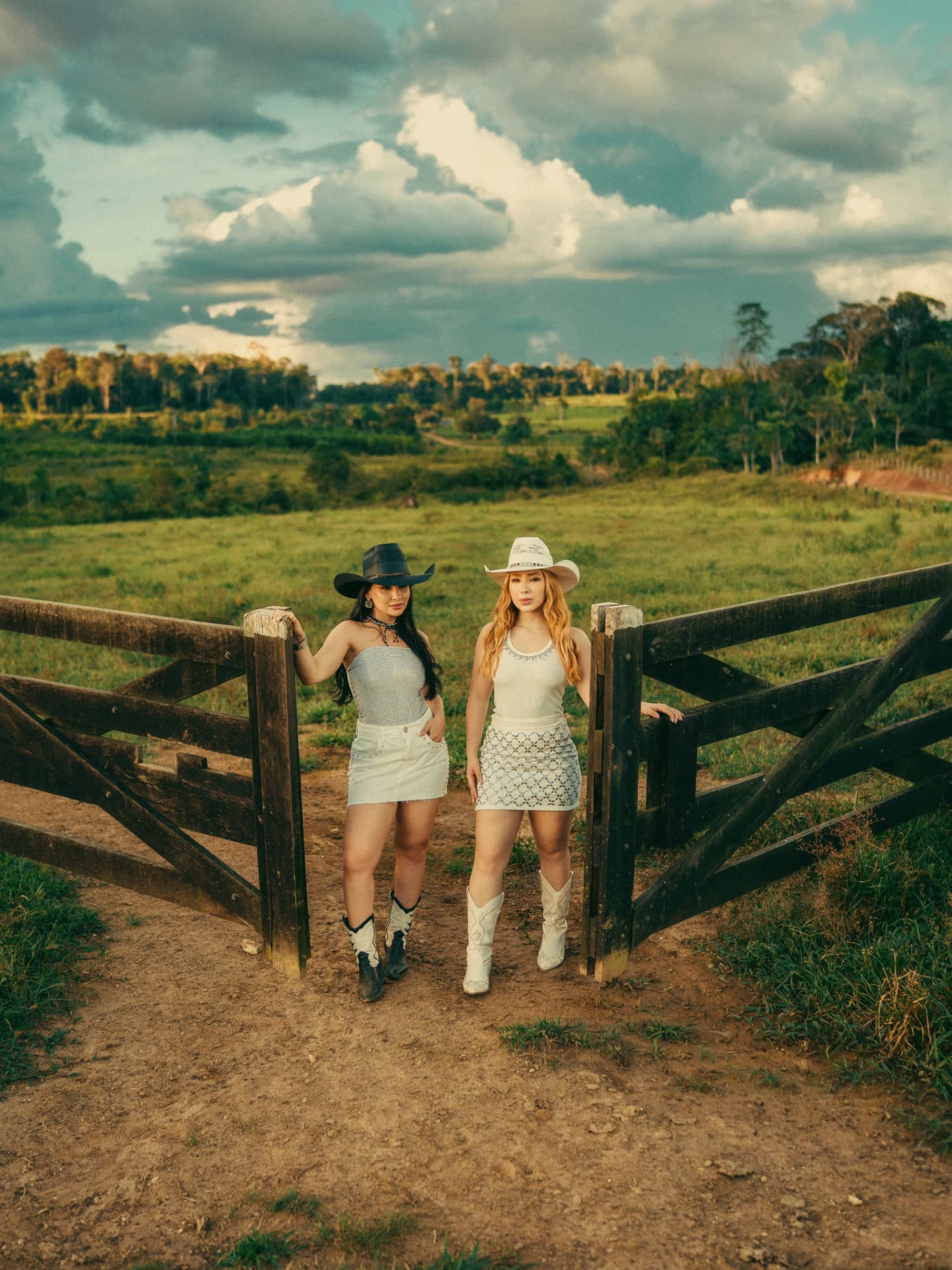 Campanha Corvée: duas mulheres na porteira da fazenda, chapéus e botas